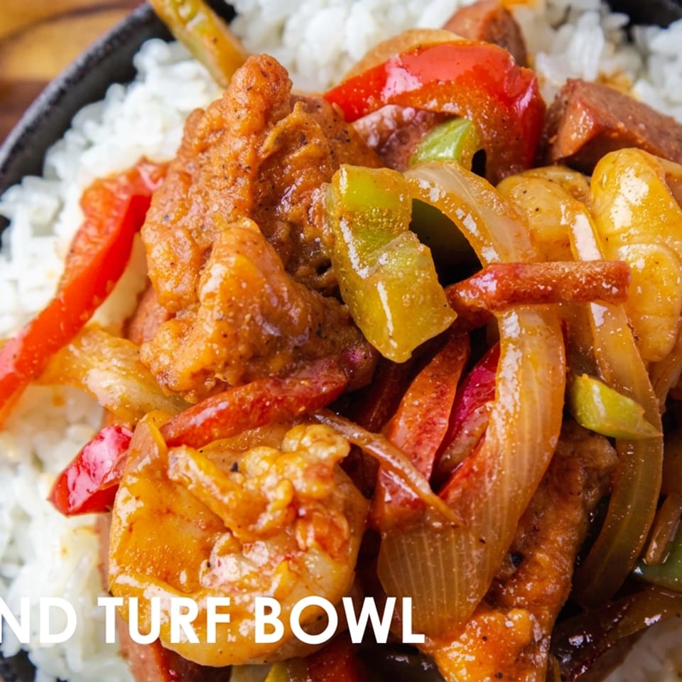 Surf and turf bowl with white rice, crispy chicken, shrimp, sautéed peppers, onions, and red chilies.