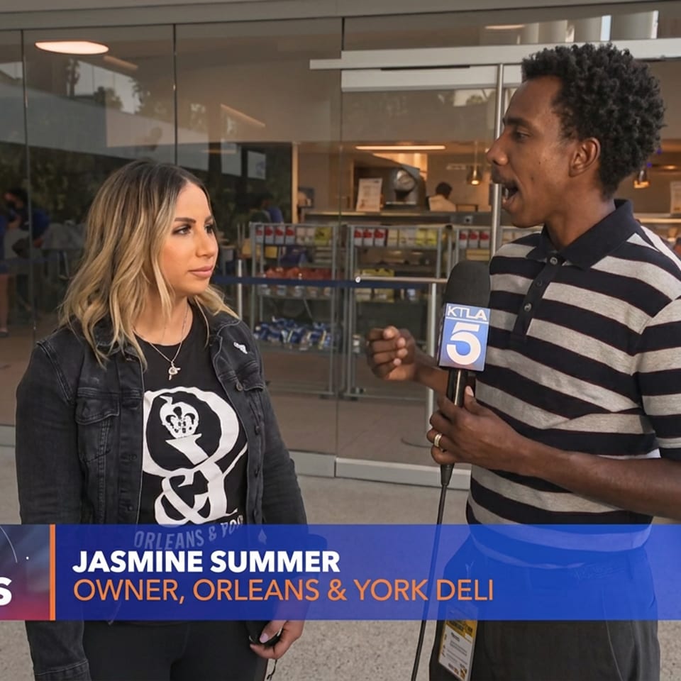 KTLA reporter interviews Jasmine Summer outside Orleans & York deli.