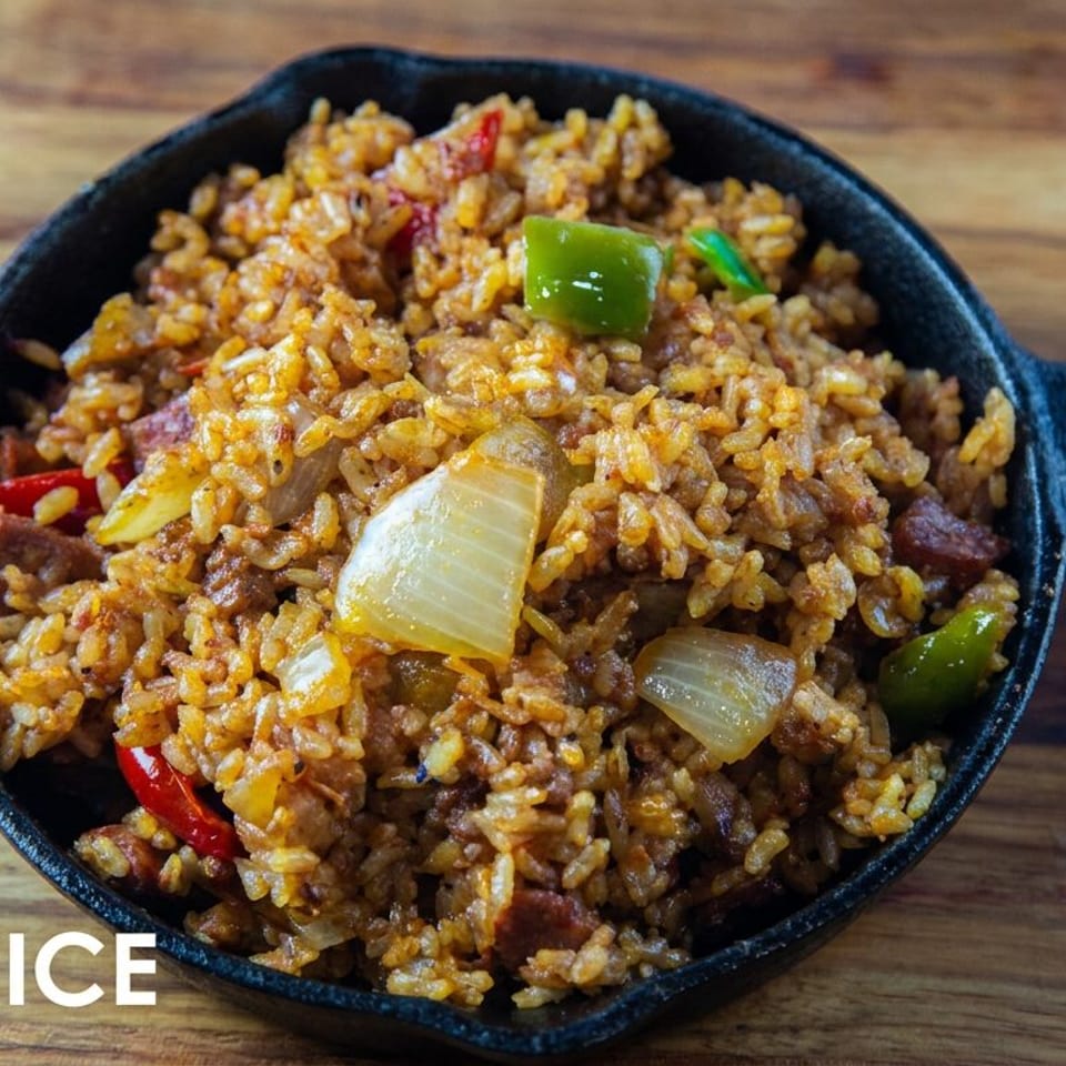 Bowl of Cajun-style dirty rice with sausage, onions, and colorful bell peppers on a wooden table.